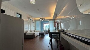 A spacious living area with a sofa, dining table, and piano.