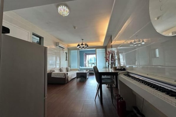 A spacious living area with a sofa, dining table, and piano.