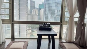 A room with a large window, a small table with teapots, and a cushioned bench.