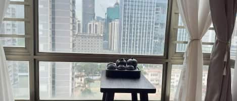 Una habitación con un ventanal grande, una mesita con teteras y un banco acolchado.