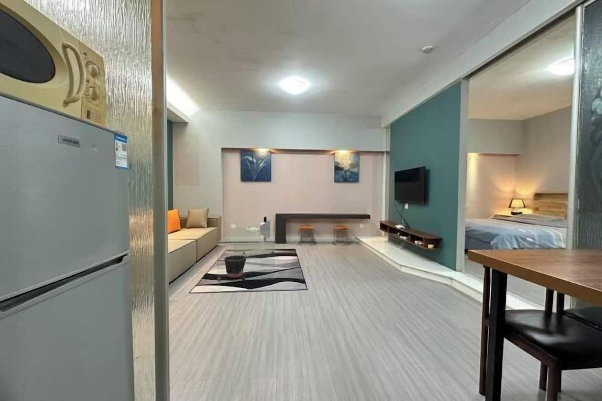 A compact hotel room with a kitchenette, a sofa, a dining area, and a bed.