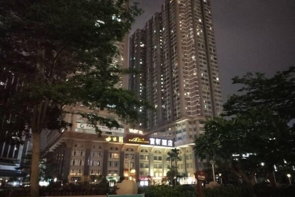 Un hotel alt amb nombroses plantes, finestres amples i senyalització il·luminada.