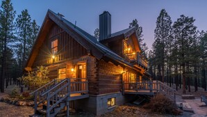 En træhytte med en stentrappe op til en terrasse, omgivet af skov.