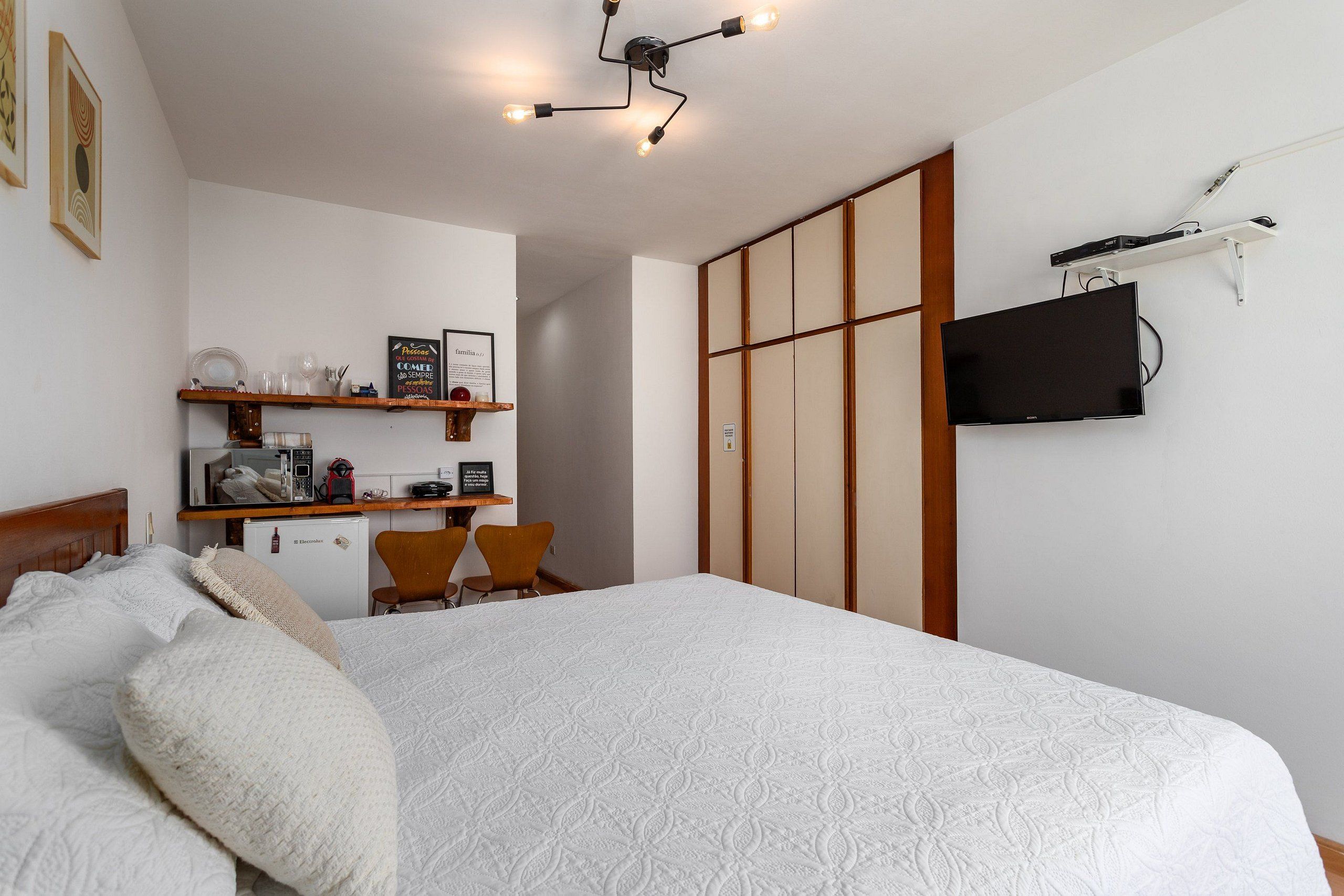Un dormitorio con una cama, un escritorio con una silla, un televisor y un armario.