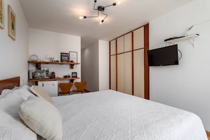 Une chambre à coucher comprenant un lit, un bureau avec une chaise, une télévision et une armoire.