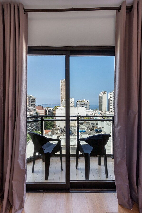 Ein Balkon mit zwei Stühlen und Blick auf Stadt und Meer.