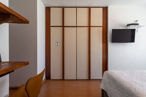A room with a wardrobe, a bed, a desk, and a television. - (902-B) Studio com Vista Mar e Comodidades (Rio de Janeiro)