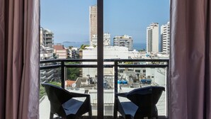 Un balcon avec deux chaises, une vue sur la ville et un ciel dégagé.