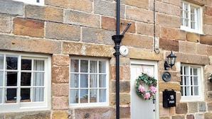 A stone building with multiple windows, a door with a wreath, and a post box.