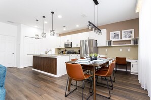 Une cuisine moderne avec des meubles blancs, des appareils en acier inoxydable et un îlot central.