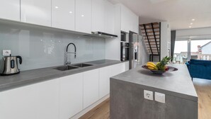 A modern kitchen with white cabinets, a stainless steel sink, and a built-in stove. There is a fruit bowl on the island and a coffee maker on the counter. - 2 bedroom stunning apartment in Pobri (Pobri)