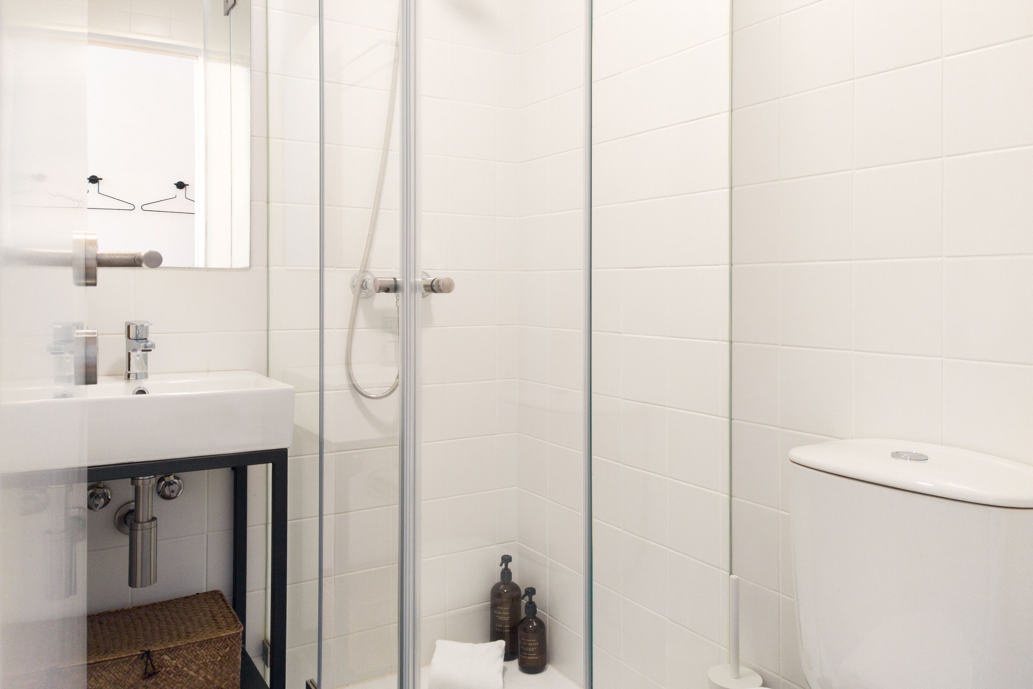 Un baño moderno con cabina de ducha de vidrio, un lavamanos con espejo y un inodoro.