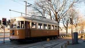 En gammal spårvagn med en skylt där det står ”Stadstur med spårvagn i Porto” står parkerad på spåren.