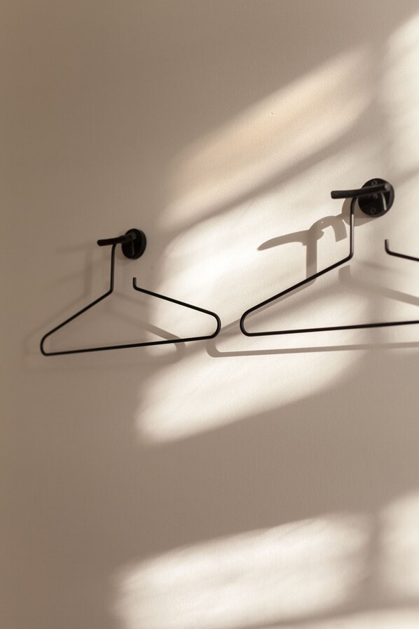 Two black metal coat hangers mounted on a wall.