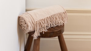 A beige towel rolled up and placed on a wooden stool against a wall. - VIVA  Alameda Suites 3 (Porto)