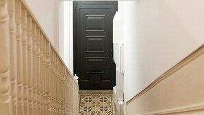 A staircase leading to a dark door with a light fixture above. - VIVA  Alameda Suites 3 (Porto)
