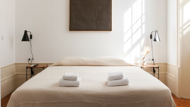 Una habitación de hotel con una cama grande, dos mesitas de noche con lámparas y un cuadro en la pared.