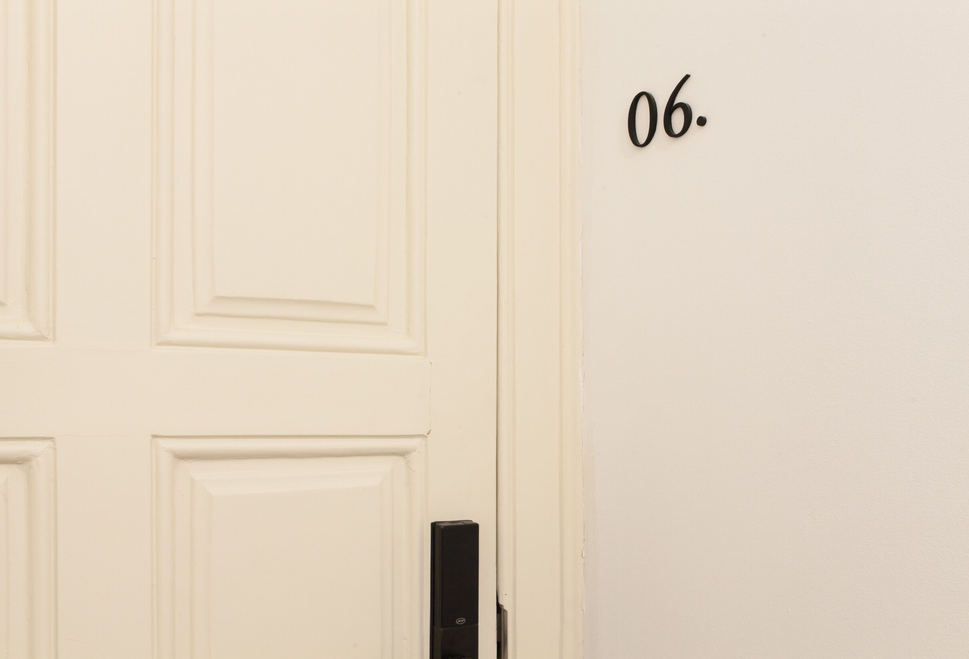 Una porta bianca con un citofono nero e il numero '06' sulla parete.