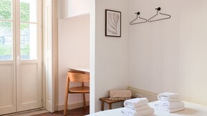 Et hotelværelse med en seng, en stol, et lille bord med håndklæder og en dør, der fører ud til en balkon.