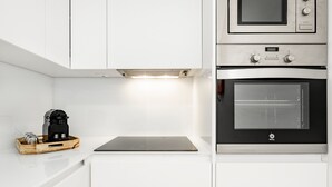 A modern kitchen with white cabinetry, a built-in oven, and a coffee machine on the countertop. - VIVA   In  the  MOOD (Porto)