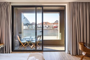 A hotel room with a large sliding glass door leading to an outdoor balcony with a table and chairs. - VIVA   In  the  MOOD (Porto)