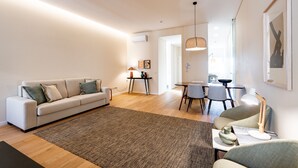 A modern living room with a sofa, coffee table, and dining area. - VIVA SIZE Flat Batalha - Apartment 2 (Porto)