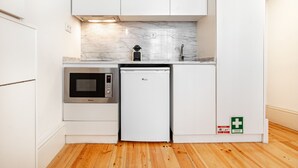 Una cocina compacta con microondas, un refrigerador pequeño y un lavamanos.