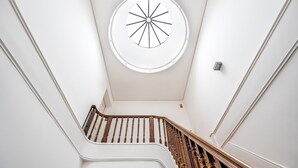 A modern staircase with wooden handrails and a circular skylight on the ceiling. - VIVA  Mosaics Studio (Porto)