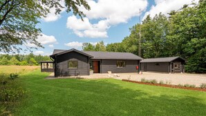 A log cabin with a gravel driveway and a grassy lawn.