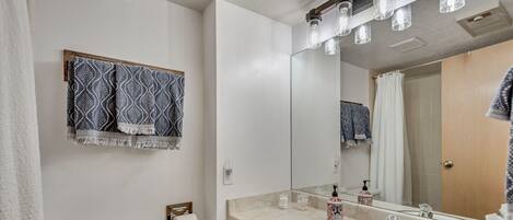 Un baño con inodoro, lavamanos, espejo y toallas estampadas.