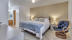 A bedroom with a bed, bedside lamps, a wicker chair, and a nightstand. - Charming condo w/ king bed, hot tub, pool, minutes away from world class skiing (Eden)