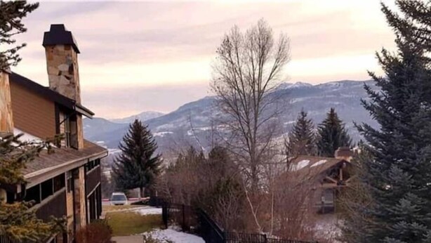 A house with a stone chimney, a snow-covered pathway, and a view of mountains. - Charming condo w/ king bed, hot tub, pool, minutes away from world class skiing (Eden)