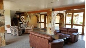 A spacious living area with a stone fireplace, leather sofas, and a staircase leading to an upper level. - Charming condo w/ king bed, hot tub, pool, minutes away from world class skiing (Eden)