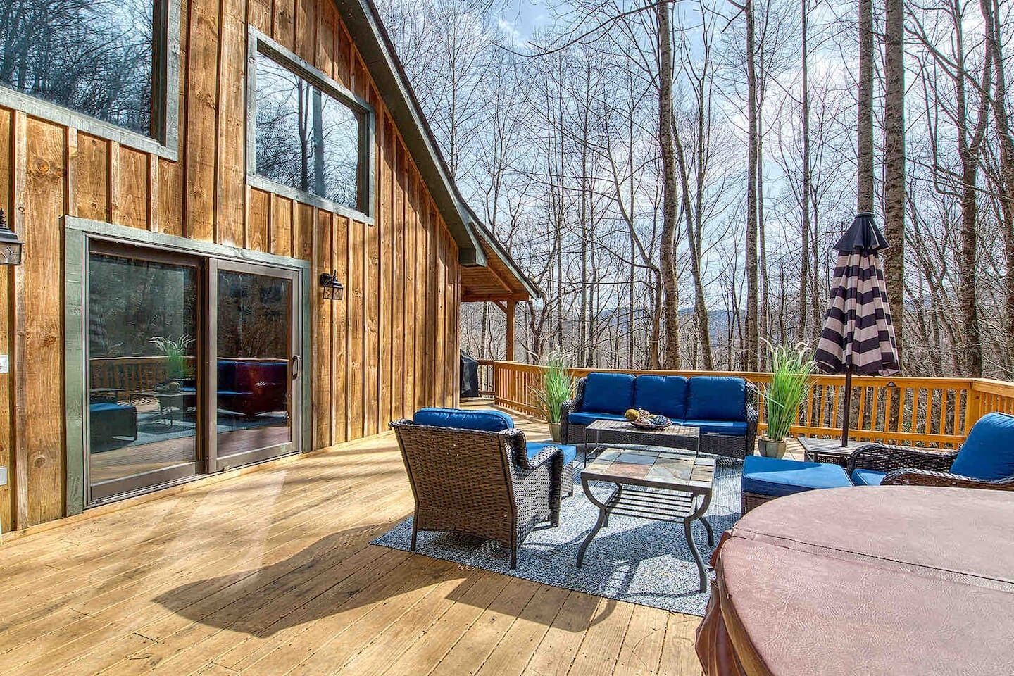 A wooden deck with outdoor furniture, including a sofa and chairs, and a glass door leading to an interior space.