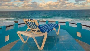 A poolside area with two lounge chairs facing the ocean, a tiled deck, and a railing. - Casa Cielo Studio 2 with detached Bayview Balcony (Isla Mujeres)