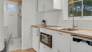 Una cocina compacta con lavavajillas, horno y lavabo.