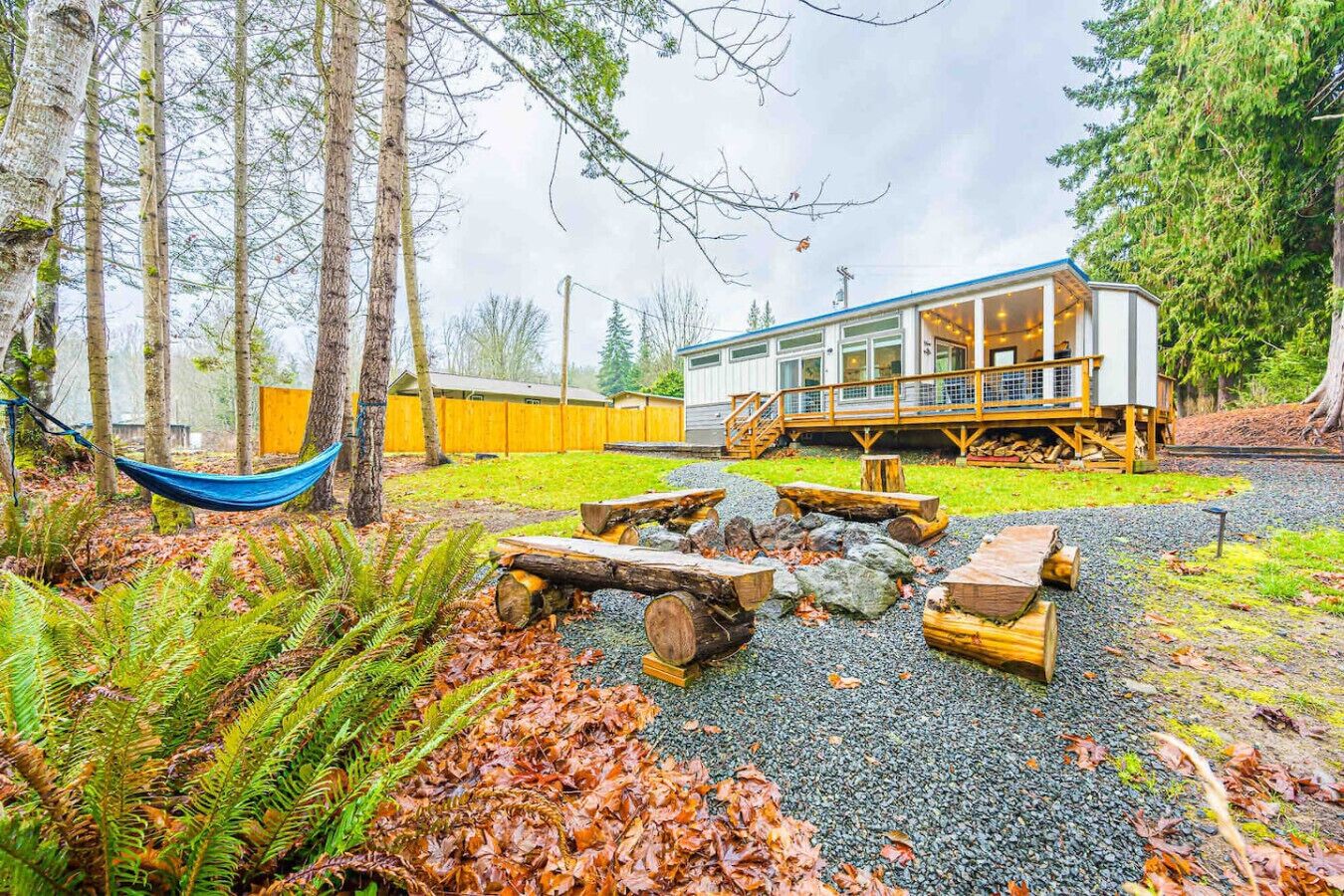 Une cabane dotée d’une terrasse, entourée d’arbres et agrémentée d’un hamac.