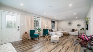 Un salon spacieux avec un grand canapé d’angle, un fauteuil turquoise et une table basse en verre.