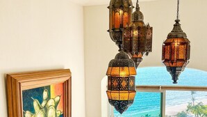 A dining area with a glass table and wicker chairs, overlooking a pool and ocean view.