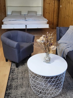 Relax in a comfortable living area with a dark blue armchair, sofa, and a large bed with a white headboard.