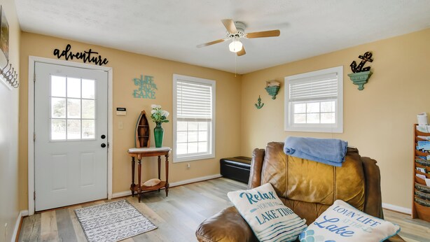 A living room with a brown leather couch, two pillows with text, a ceiling fan, and a door labeled "adventure". - 8 Mi to Cave Run Lake Boating: Outdoor Retreat! (Wellington)