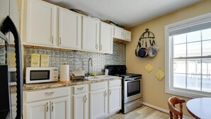 A kitchen with white cabinets, a microwave, a stove, and a window with a view. - 8 Mi to Cave Run Lake Boating: Outdoor Retreat! (Wellington)