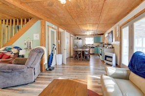 A spacious living area with a dining table, sofas, a kitchen, and a staircase.