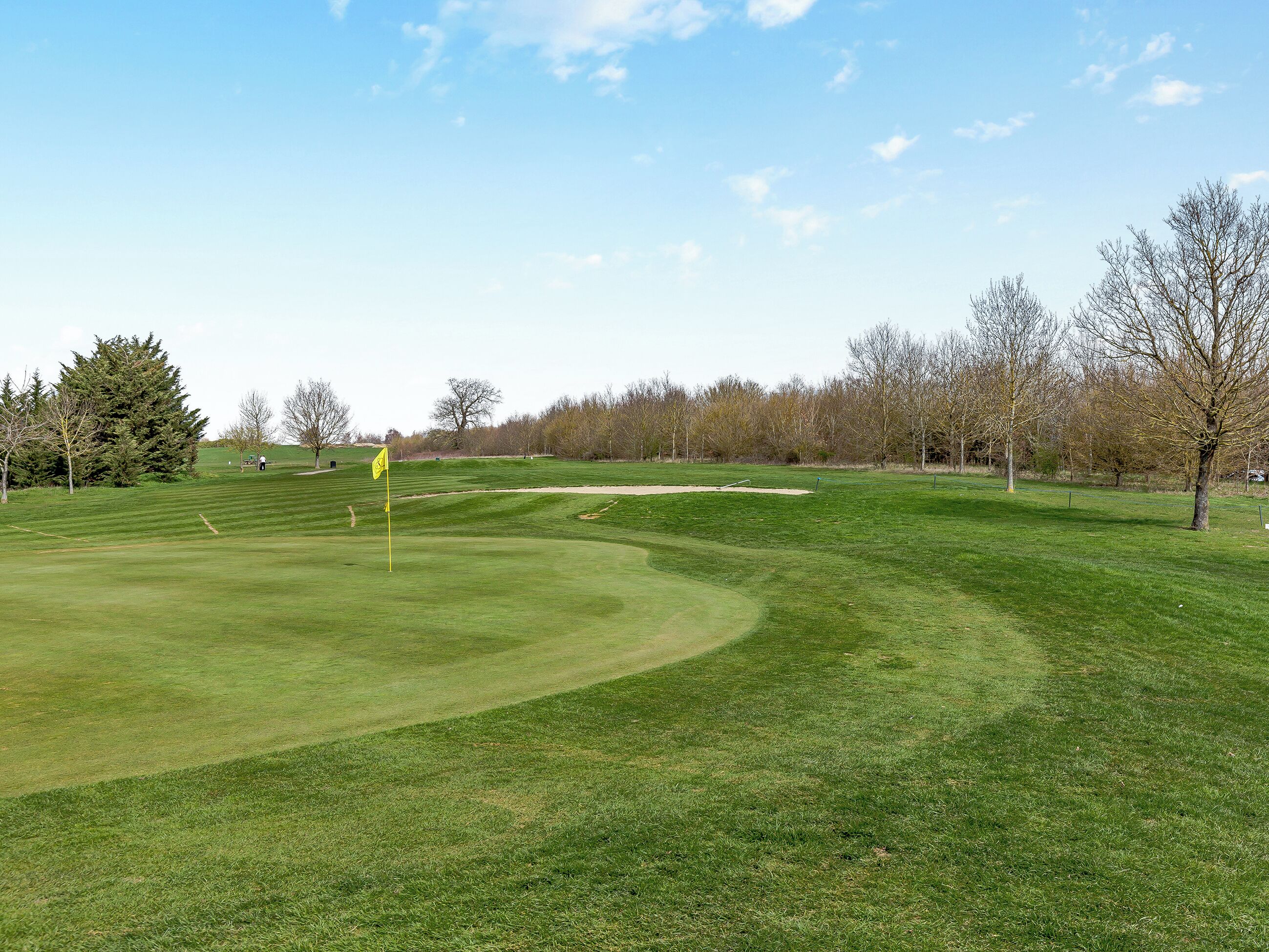 A golf course with a flag, sand bunkers, and trees.