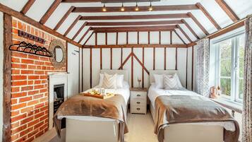A cozy bedroom with two beds, a fireplace, and a window with curtains.