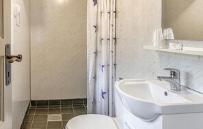A bathroom with a white sink, a toilet, a shower with a white curtain, and a mirror above the sink. - Gorgeous home in Offersøy with sauna (Offersøy)