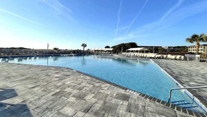 Ein Swimmingpool mit Liegestühlen und Sonnenschirmen, umgeben von Gebäuden.