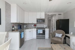 A compact kitchen with white cabinets, a microwave, and a black refrigerator.