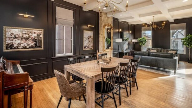 A dining area with a wooden table and chairs, a piano, and artwork on the walls. - Cream City Victorian Parking AC Patio Walkable (Milwaukee)