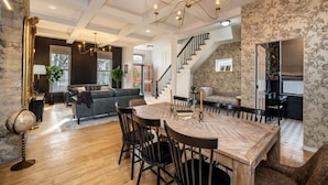 A spacious living area with a wooden dining table, black chairs, and a staircase leading to another level. - Cream City Victorian Parking AC Patio Walkable (Milwaukee)